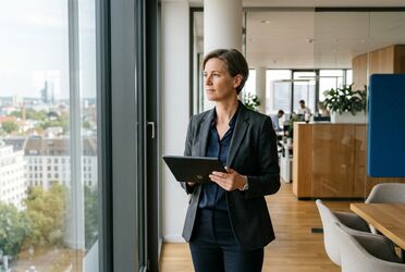 Entscheiderin im Mittelstand mit Tablet im hellen Besprechungsraum, souveräne Führung im Unternehmen