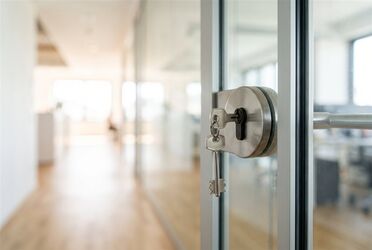 Schlüssel steckt im Schloss einer Glastür in einem hellen Büro