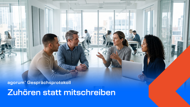 Helle Besprechung am Fenster, zwei Personen im Gespräch, auf dem Tisch liegt ein Smartphone