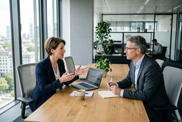 Zwei Entscheider im Mittelstand besprechen an einem Laptop die Wahl des passenden KI-Modells