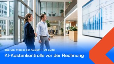 Zwei Führungspersonen betrachten in einer hellen Bürohalle ein Kostendiagramm auf einer großen Wandanzeige