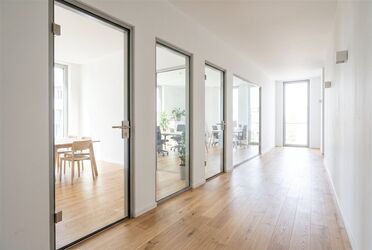 Heller Flur mit drei Glastüren, die in unterschiedliche helle Räume führen