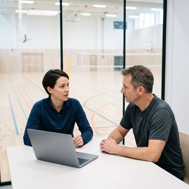 Beratungsgespräch an einem hellen Tisch vor der Sporthalle