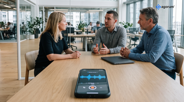 Besprechung an einem Tisch, davor zeichnet ein Smartphone mit ALBERT | AI Note das Gespräch auf