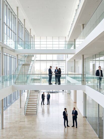 Lichtes Atrium eines Finanzhauses mit Galerien, Treppe und Beratenden in Gesprächsgruppen